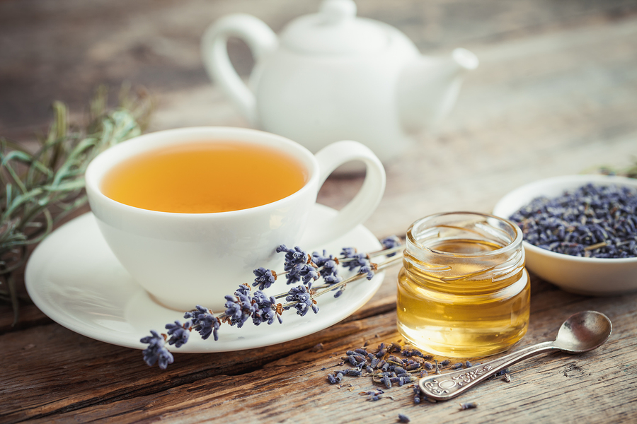 Healthy tea cup jar of honey dry lavender flowers and teapot on background. Selective focus. Retro styled.